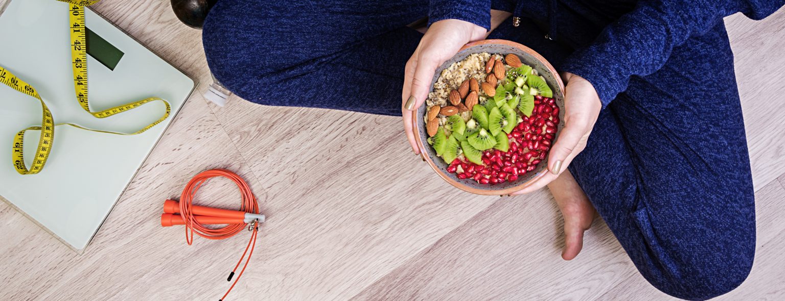 Fitness and healthy lifestyle concept. Female is resting and eating a healthy oatmeal after a workout. Banner. Top view.